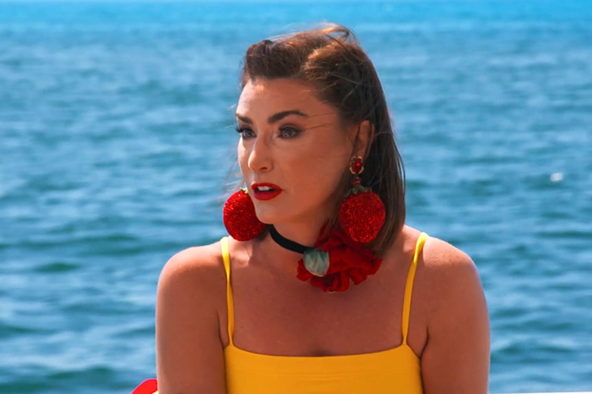 Bronwyn Newport wearing strawberry earrings and a yellow top while on a boat.