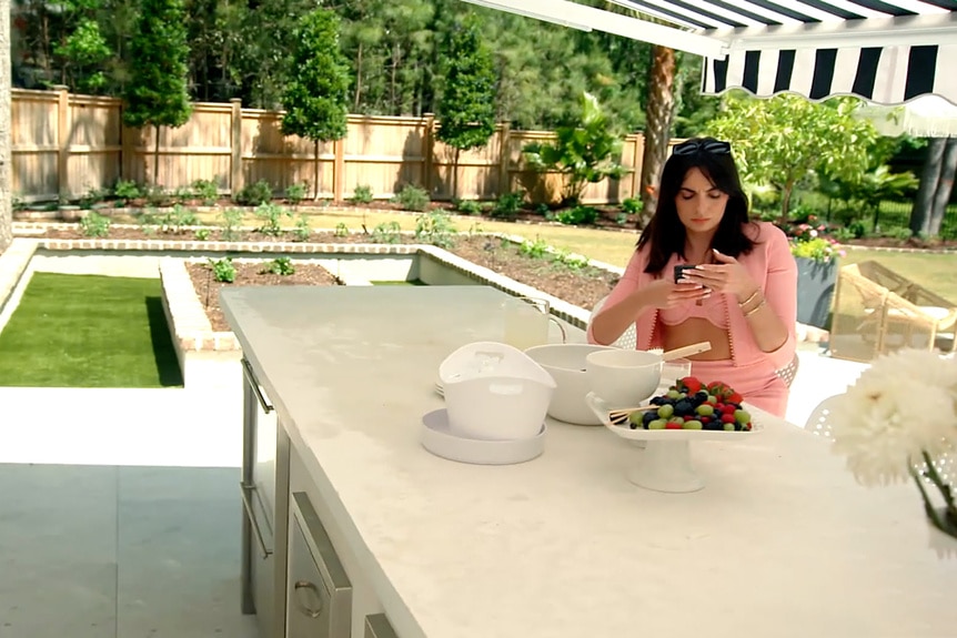 Paige DeSorbo wearing a pink bathing suit in Craig Conover's backyard.