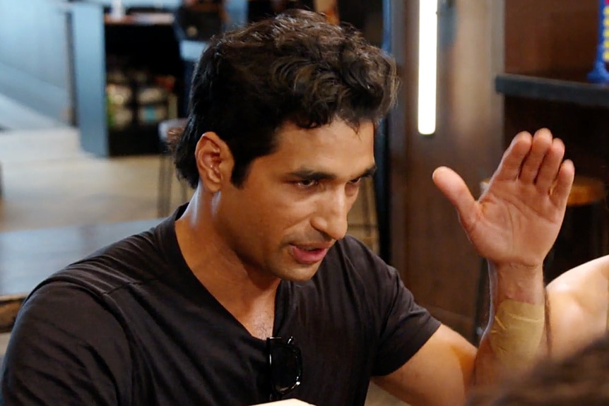 Imrul Hassan wearing a black tee shirt in mid conversation at a restaurant