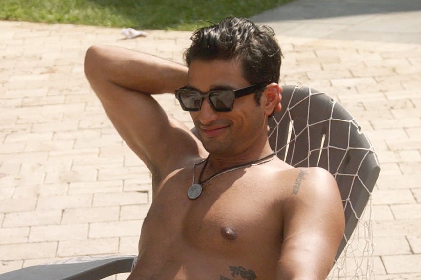 Imrul Hassan sitting on a lounge chair without a shirt on by the pool