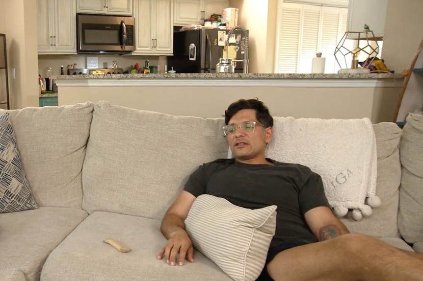 Rodrigo Reyes sitting on Taylor Ann Green's couch with her kitchen in the background