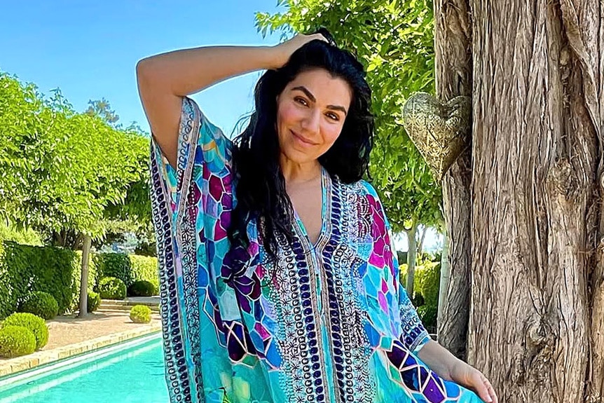 Asa Soltan wearing a blue print kaftan in front of a pool