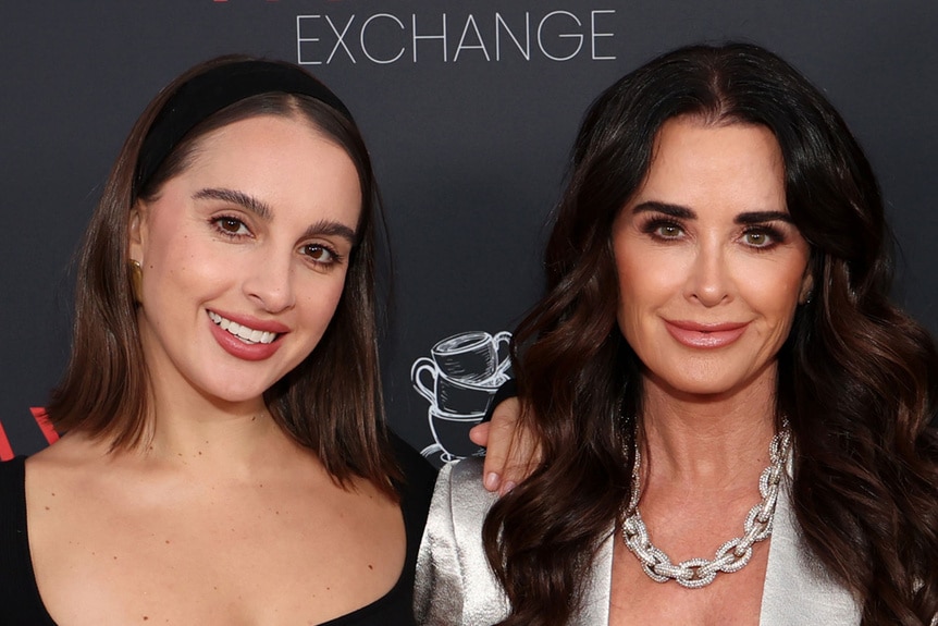 Kyle Richards and Alexia Umansky smiling in front of a step and repeat.