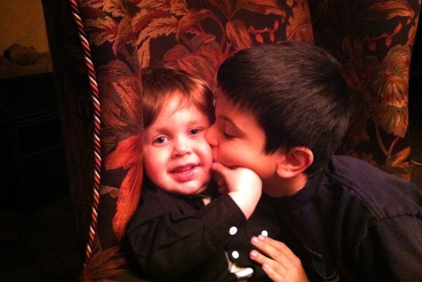 CJ Laurita kissing his younger brother Nicholas on the cheek in a chair as children